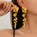Detailed close-up showing long gold metallic flower drop earrings worn by a model - Style 4 Gold