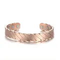 Detail view of rose gold magnetic therapy alloy cuff bracelet with striped texture. - Rose Gold