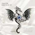 Vintage punk mechanical dragon brooch featuring detailed wings gears and a blue eye center - Dragon Brooch - Silver Grey
