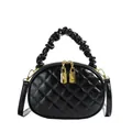 Detailed view of the black quilted handbag with unique ruffled top handle and gold zippers. - Black
