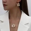 Elegant white enamel flower jewelry set featuring a gold necklace and earrings on a model - Flower Necklace Earring Set / White
