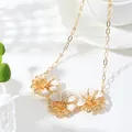 Detailed view of vintage gold enamel flower necklace with three white floral pendants. - Necklace
