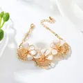 Close-up of elegant gold bracelet featuring white enamel flower charms and adjustable chain - Bracelet
