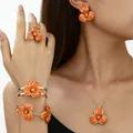 Detail shot of orange enamel flower necklace, earrings, and bracelet set on a model - Jewelry Set / Orange