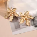 Close-up detail of textured gold-tone exaggerated floral earrings with pleated petals. - Style 11 Gold