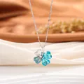 Gros plan d'un collier trèfle à quatre feuilles en argent avec cristaux de cœur bleus. - Style Trèfle à Quatre Feuilles / Bleu lac