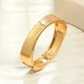 Vista dettagliata del bracciale rigido in metallo dorato lucido con chiusura a molla. - Stile 7 / Oro