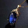 Close-up of a luxurious blue oval gemstone pendant with gold frame and small crystals - Blue