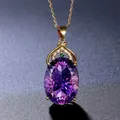Detailed macro view of an oval-cut amethyst pendant with ornate gold and emerald accents - Purple