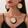 Detail eines Vintage-Schmucksets aus Metallscheiben mit gold-schwarzen geometrischen Anhängern - Halsketten- und Ohrring-Set / Gold