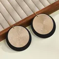 Vista de detalle de pendientes geométricos con discos texturizados en oro y negro superpuestos - Pendientes tipo gota / Dorado