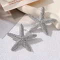 Macro view of textured silver starfish earrings with a shimmering hammered finish detail - Earrings Only / Silver