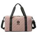 Detail view of the pink quilted duffel bag showing the brand logo and texture. - Dusty Pink