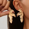 Macro view showing the intricate texture of gold leaf alloy earrings on a model's ear - Style 3 Gold
