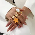 Detailaufnahme von Barockperlen- und orangefarbenen Blumenringen an der Hand in Weiß - Stil 1 (BGZ-267) / Gold