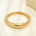 Dettaglio ravvicinato di un bracciale rigido ovale liscio dorato minimalista da donna - Stile 8203 / Oro