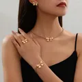Detailed view of an elegant gold metal bow necklace and bracelet jewelry set worn by a model - Bow Jewelry Set
