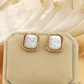 Close-up of elegant square gold-plated earrings with textured baroque pearl inlay. - Square Studs