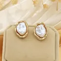Close-up of elegant irregular baroque pearl stud earrings in a polished gold frame - Stud Earrings / Gold