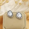 Detailed view of elegant irregular pearl stud earrings with a silver-tone wavy border. - Stud Earrings / Silver