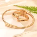 Dettaglio di un set di gioielli dorati minimalisti con design a onde irregolari - Stile 10 Set Choker e Bracciale Rigido Grande / Oro