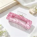 Detailed macro shot of large pink marbled acrylic hair claw clip with golden spring - Magenta Marble