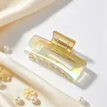Detailed view of iridescent UV-plated square hair claw clip set on soft silk fabric. - Gradient Champagne
