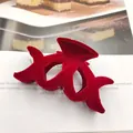 Detail van een rode geflokte fluwelen haarklem op een tijdschriftpagina - Kruis Ontwerp / Bordeauxrood