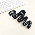Detail view of a glossy black wavy hair claw clip on a minimalist desk background - Glossy Black