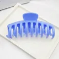 Macro view of large blue plastic hair claw clip displayed on a minimalist white tray - Sky Blue