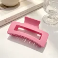 Détail d'une pince à cheveux carrée rose mat posée sur une table blanche épurée - Rose Foncé Mat