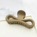 Close-up of a large matte khaki hair claw clip featuring a unique bow-shaped design. - Medium Coffee