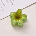 Detail view of a 4cm green frangipani flower hair claw clip with yellow gradient - Green + Green