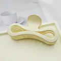 Close-up of large matte cream bow-shaped hair claw clip on a white tray - Ivory