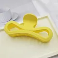 Close-up of large yellow matte hair claw clip with hollowed figure-eight design on tray - Yellow