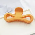 Close-up detail of large orange matte infinity hair claw clip with smooth texture - Orange