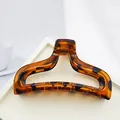 Detailed close-up of a large tortoiseshell acrylic hair claw clip on a white tray - Glossy Leopard Print