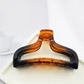 Close-up of amber and black gradient shark hair claw clip on white tray - Shiny Tortoise Shell