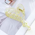 Nahaufnahme einer gelben transparenten herzförmigen Acryl-Haarklammer auf Magazin - Glänzend Champagner