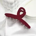 Detailed view of a large burgundy red velvet hair claw clip placed on white silk fabric - 11 Streamer Style / Burgundy