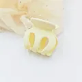 Close-up view of a matte yellow small hair claw clip placed on soft fabric background - Ivory
