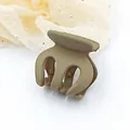 Close-up macro view of small khaki matte hair claw clip against cream rhinestone fabric - Khaki