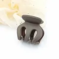 Detailed close-up view of a small matte dark brown hair claw clip for hair styling - Coffee