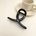 Detailansicht einer minimalistischen schwarzen Haarklammer auf cremigem Hintergrund - Glänzendes Schwarz