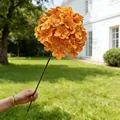 Einzelner Stiel leuchtend orangefarbener künstlicher Hortensienblüten für die Dekoration. - Orange