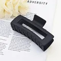 Close-up detail showing the premium matte black texture of a large square hair claw clip - Black