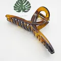 Detail view of a large amber PC hair claw clip with minimalist cross design - Ribbon Style (17) / 13cm Version / Brown Tortoise Shell