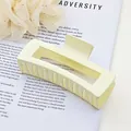 Macro view of a matte cream square hair claw clip placed on a book page with English text - Ivory