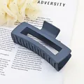 Close-up of matte dark blue square hair claw clip on magazine background - Gray