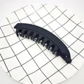 Detailed macro view of a black matte banana hair clip on a grid plate background - Matte Black